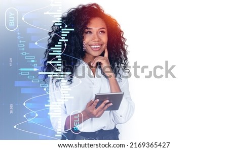 Smiling pensive black businesswoman portrait using tablet, forex diagrams hologram with candlesticks, buy and sell. Concept of online trading and consulting. Copy space Royalty-Free Stock Photo #2169365427
