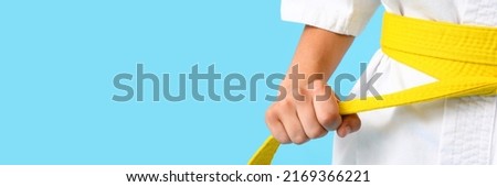 Little boy in karategi and with yellow belt on light blue background with space for text, closeup Royalty-Free Stock Photo #2169366221