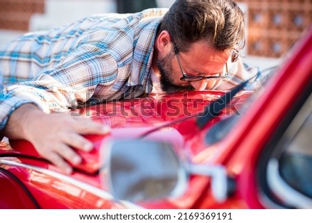 Man kiss his new car. Automobile lovers and owner hugging his vehicle. Concept of dreams and buying. Satisfied guy with closed eyes embracing  the automobile. Dreaming man lying on car kissing it Royalty-Free Stock Photo #2169369191