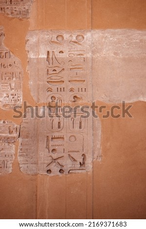 Real Ancient Egyptian hieroglyphics engraved in a stone wall in Luxor Egypt