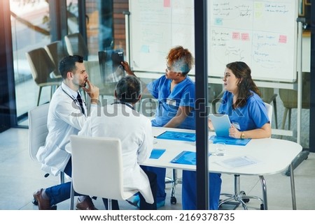 Discussing the problem at hand. Shot of a group of medical practitioners analyzing x-rays in a hospital.