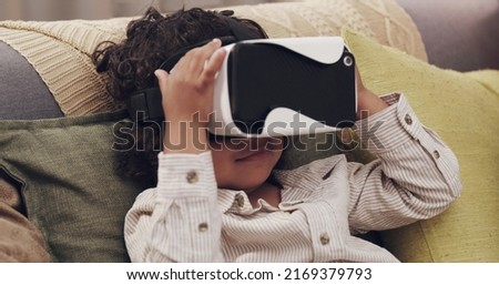 Glued to the screen. Shot of a little boy watching movies together through virtual reality headsets at home.