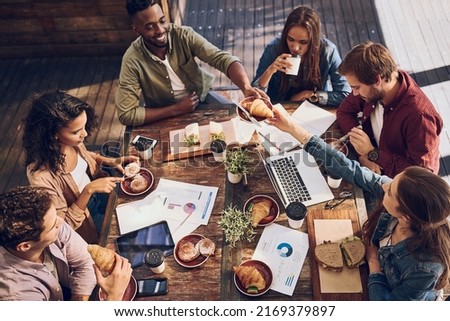 Catching up on statistics while enjoying a good bite. Shot of a group of creative workers having a meeting over lunch in a cafe. Royalty-Free Stock Photo #2169379897