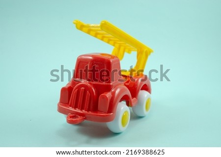 Red paint plastic toy fire truck with yellow ladder isolated on blue background