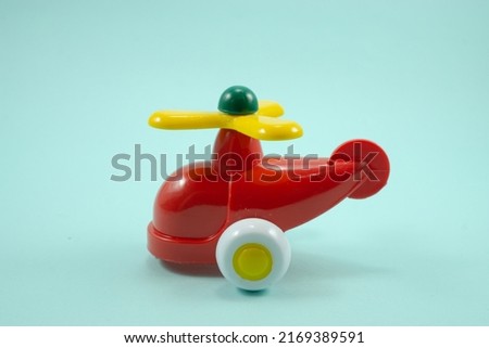 red paint plastic toy helicopter with yellow propeller isolated on blue background