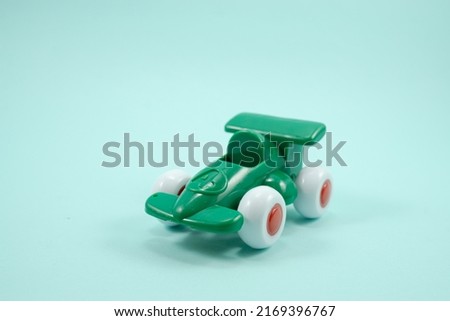 Green paint plastic toy racing car with number one isolated on blue background.