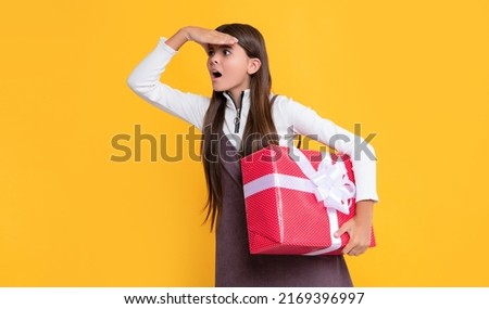 amazed kid with present box on yellow background