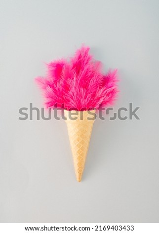 Creative arrangement made of cornet and pink feathers on a gray background. Minimal ice cream concept.