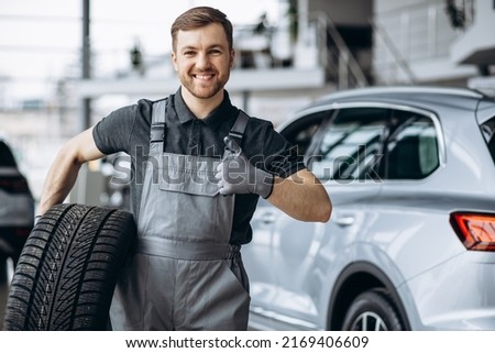 Workman at car repair shop changing tires Royalty-Free Stock Photo #2169406609