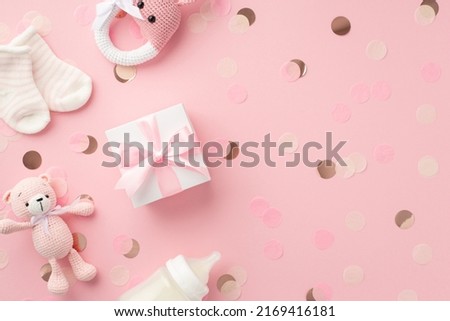 Baby girl concept. Top view photo of gift box tiny socks knitted bunny rattle toy teddy-bear toy milk bottle and shiny confetti on isolated pastel pink background