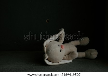 Toy bunny lies alone in a room. War, death and lost childhood concept. Royalty-Free Stock Photo #2169419507