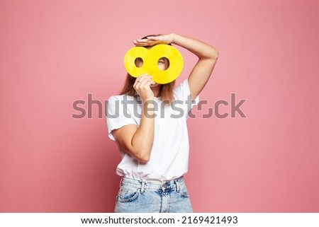 Happy woman in white blank t-shirt behind yellow number eight banner on pink