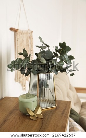Stylish glass vase with eucalyptus branches and beautiful decor elements on wooden table indoors Royalty-Free Stock Photo #2169422637