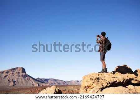 Young man taking pictures on a road trip. Man making memories on the mountain.