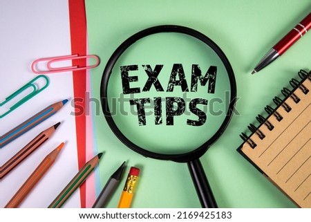 Exam Tips. Magnifying glass and stationery on a green background.