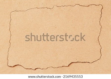 Kraft paper with burnt edges on kraft background, copy space