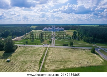 Fields with hay in the foreground. Kossovo castle with beautiful red roof in the background.Restored ancient castle-palace of Paslovsky Kosovo, Belarus. aerial view height