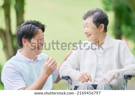 Asian senior aged woman talking with a caregiver outdoor