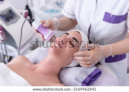 A young woman undergoing a facial radiofrequency face lift treatment. Facial skin care treatment, anti-aging facial rejuvenation. Beauty and dermatology concept. Royalty-Free Stock Photo #2169462641