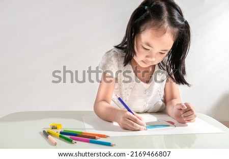 A little toddler girl doing arts and crafts work at home drawing sketching with colorful paint using color pencil. Child education at home during a lockdown. Concept of art and creativity of children.
