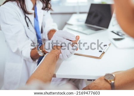 Closeup shot of a nurse holding a patient's hand in comfort. Close-up of home caregiver and senior woman holding hands.  Female patient listening to doctor in medical office. Support people 