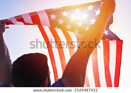 Man with waving American Flag against clear blue sky. Independence day of United States of America. Concept of American patriotic people