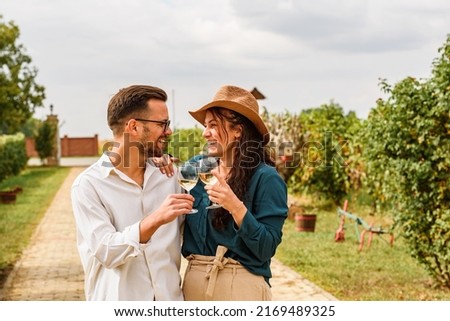 Young smiling couple tasting wine at winery vineyard - Friendship and love concept with young people enjoying harvest time  Royalty-Free Stock Photo #2169489325