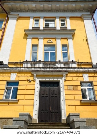 06.04.2022 Kyiv, Ukraine. 
Dark door at the yellow wall. Entrance to historical building. wrought iron elements and coverings over the door.  stucco on the facade of the building.  