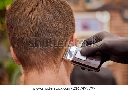 Male haircut shaving in barbershop, client getting haircut by hairdresser with electric shaver. Hairdresser makes hairdo in hairdresser salon, new stylish modern haircut for man Royalty-Free Stock Photo #2169499999