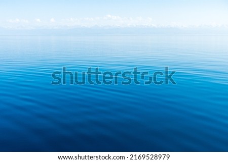 Clear water texture in blue and orange. Background of the ocean and the sea backlit by the sun.