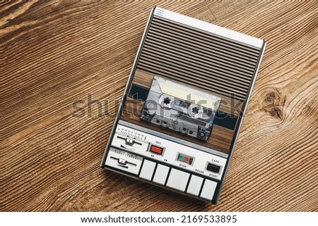 Compact cassette tapes and cassette recorder on wooden table. Retro music style. 80s music party. Vintage style. Analog equipment. Stereo sound. Back to the past Royalty-Free Stock Photo #2169533895