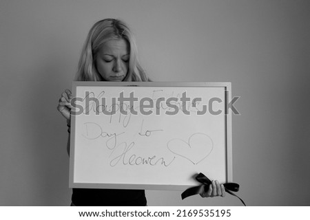 young woman holding big blackboard with greeting. celebrating international holidays in 2022. happy fahters day to heaven. death. tragedy.