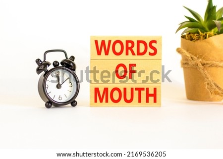 Words of mouth symbol. Concept words Words of mouth on wooden blocks on a beautiful white table white background. Black alarm clock. Business, finacial and words of mouth concept. Copy space.