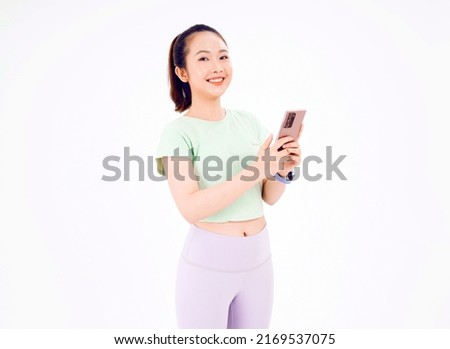 Young Asia lady show empty smart phone screen with positive expression, smiles broadly, dressed in casual clothing feeling happiness on blue background. Mobile phone with white screen in female hand.