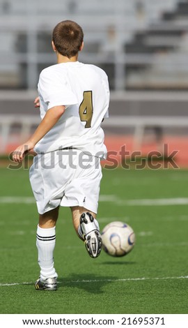Teen soccer player running after the ball on the field