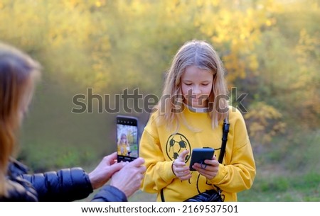 Girl with her mom taking photo with phone camera outdoors