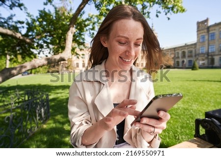 Lady with smile presses her finger on the smartphone screen