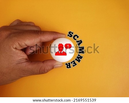 Hand holding white ball table tennis with icon of alert and text written scammer on background 