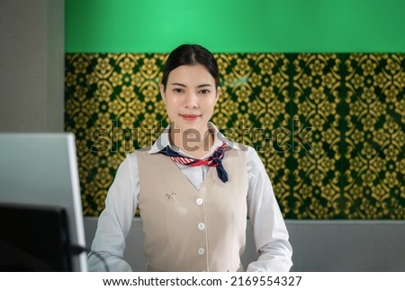 Portrait of beautiful Asian woman airport ground attendant in uniform and standing smile looking on camera at counter check in. Happy young female ground stewardess wait service for airline business.