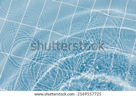 Clear water surface with ripple wave splashes and drops in swimming pool. Abstract turquoise or blue texture water wave and sunlight shadow reflections for background Royalty-Free Stock Photo #2169557725