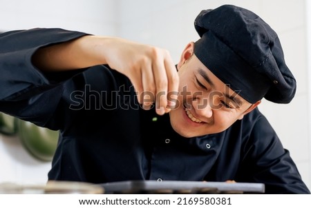 Portrait, close up handsome Asian Japanese professional chef wearing black uniform, smiling with happiness, cooking and decorating dish. Hotel or Restaurant Service Concept Royalty-Free Stock Photo #2169580381