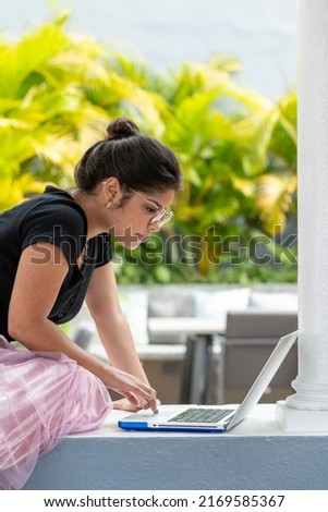 Portrait of latin young woman using laptop outdoors - stock photo