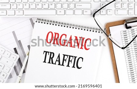Text ORGANIC TRAFFIC on Office desk table with keyboard, notepad and analysis chart on a white background. Royalty-Free Stock Photo #2169596401