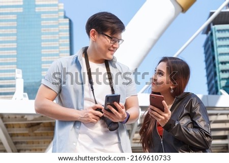 asia city travel. smiling happy young asian couple looking at smartphone to search for travel information and location map from traveling application. technology and travel concept.  