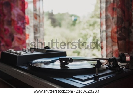 The head and needle of an old Soviet gramophone. Vintage music player with a vinyl record on the window on a summer day. Space for text, retro background for design.