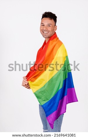 Gay man smiling with pride flag over his shoulders. High quality photo