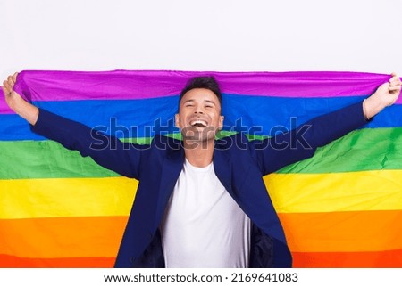 Gay man wearing a suit and raising the pride flag. High quality photo