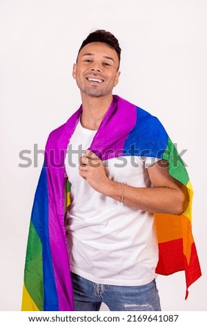 Smiling gay man holding the pride flag . High quality photo