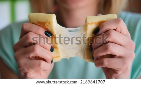 Close-up of female hands holding pancake with cheese filling. Woman stretching slapjack with cheese. Home cooking and healthy food concept Royalty-Free Stock Photo #2169641707