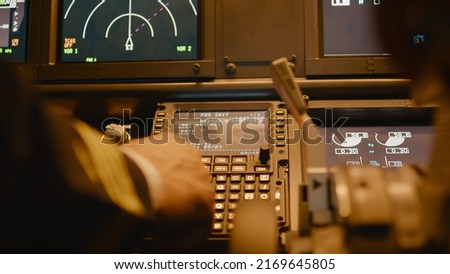 Captain inserting destination coordinates on cabin dashboard, using control panel command to fly airplane. Piloting plane with engine throttle, power switch and radar. Close up.